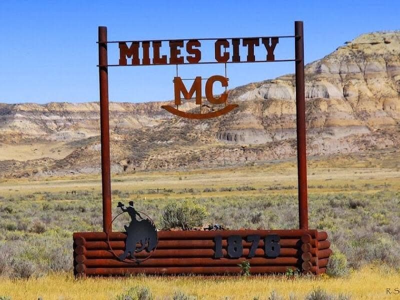The Miles City welcome sign standing in front of the badlands
